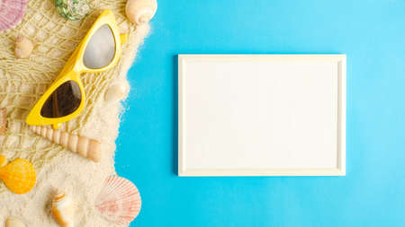 summer sunlight concept.white blank picture frame on sand with beach accessory on blue sea backgroundの写真素材
