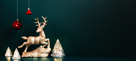 Christmas gold reindeer with xmas tree lamp lights with red baubles hanging on dark blue green background.banner mockup for display of design or invitation card for holiday eventの写真素材