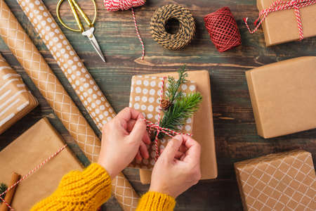 Hand tied rope on christmas gift box with brown paper decor with pine fir on wood tableの写真素材