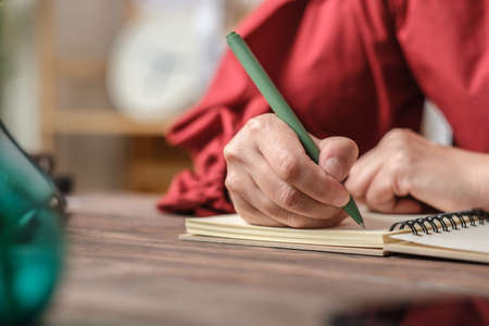 close up hand writing on notebook on wooden tableの写真素材