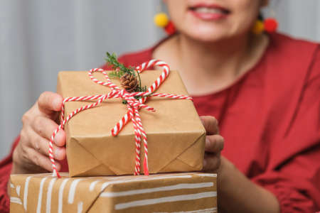 woman making Christmas handmade gift box with brown paper warpping with xmas decor on wood tableの写真素材