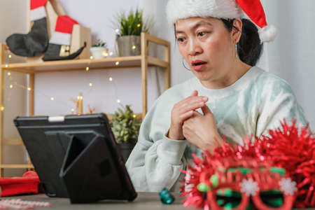 asian woman celebrate new year and christmas party with tablet video call friends at homeの写真素材
