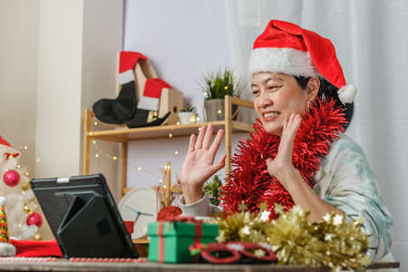 asian woman celebrate new year and christmas party with tablet video call friends at homeの写真素材