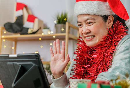asian woman celebrate new year and christmas party with tablet video call friends at homeの写真素材