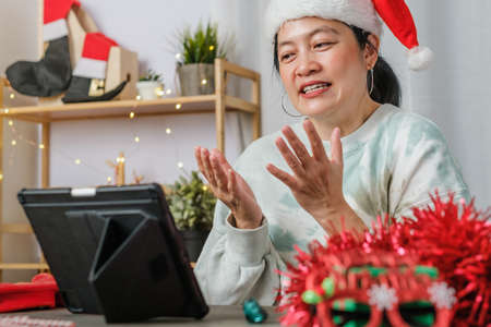 asian woman celebrate new year and christmas party with tablet video call friends at homeの写真素材