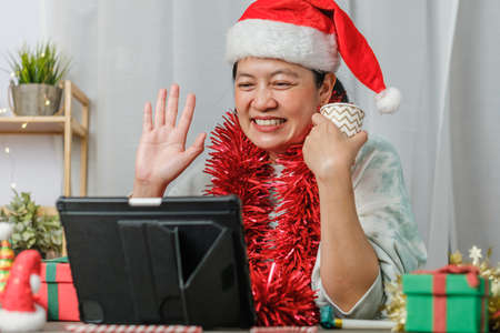asian woman celebrate new year and christmas party with tablet video call friends at homeの写真素材