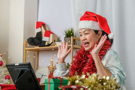 asian woman celebrate new year and christmas party with tablet video call friends at homeの写真素材