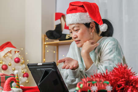 asian woman celebrate new year and christmas party with tablet video call friends at homeの写真素材