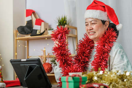 asian woman celebrate new year and christmas party with tablet video call friends at homeの写真素材