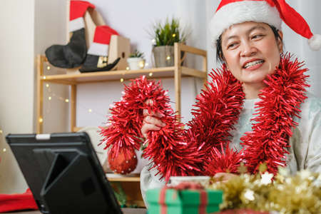 asian woman celebrate new year and christmas party with tablet video call friends at homeの写真素材