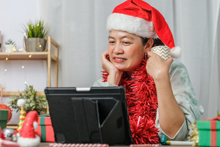 asian woman celebrate new year and christmas party with tablet video call friends at homeの写真素材