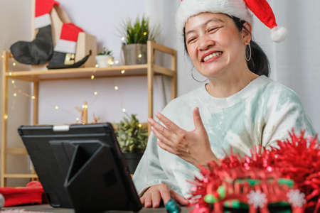asian woman celebrate new year and christmas party with tablet video call friends at homeの写真素材