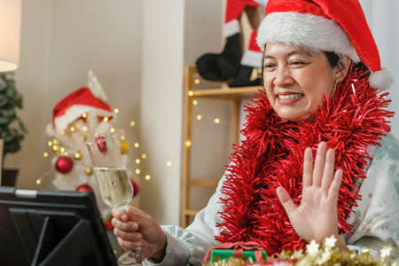 asian woman toasting champagne celebrate new year and Christmas party video call friends at homeの写真素材
