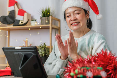 asian woman celebrate new year and christmas party with tablet video call friends at homeの写真素材