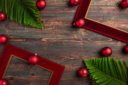 Christmas red picture frame with pine leaf and bauble decor on wood tableの写真素材