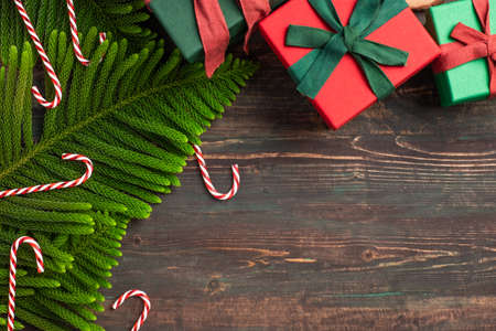 Christmas colorful gift box with pine leaf and decoration ornament on wooden table
