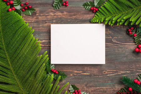 Christmas greeting card mockup with pine leaf and mistletoe on wooden tableの写真素材