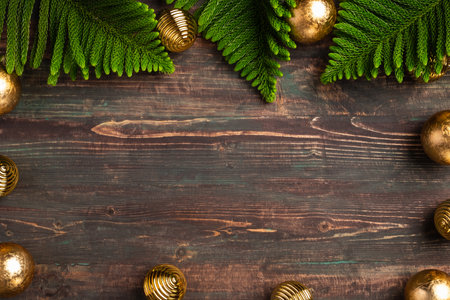 Christmas pine leaf with golden bauble decoration on wooden tableの写真素材