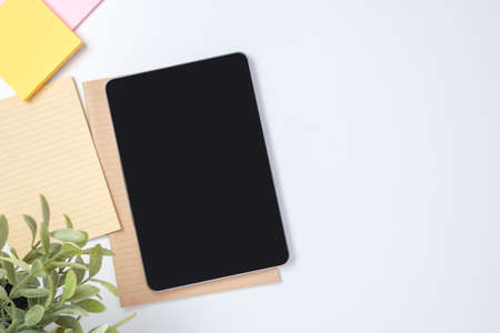 top view working desk with tablet blank screen and notebook on white table backgroundの写真素材
