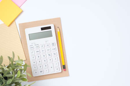 top view working desk with calculator and notebook on white table backgroundの写真素材