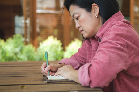 woman writing goal on notebook  at coffee shop outdoor spaceの写真素材