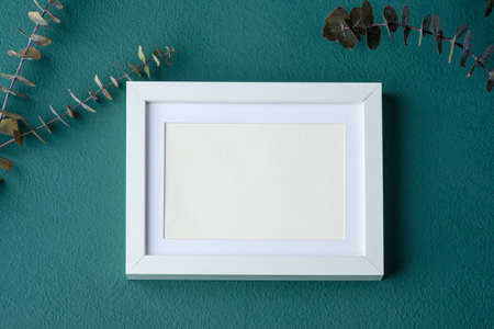 photo frame mockup with eucalyptus branch on green table