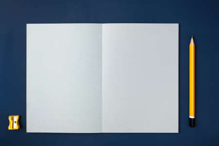 top view open notebook with yellow pencil and notepad on navy blue working tableの写真素材