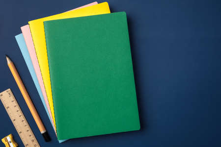 top view pastel notebook with yellow pencil and notepad on navy blue working tableの写真素材