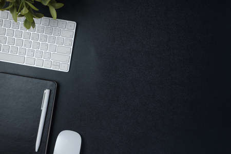 top view working desk with keyboard mouse and notebook on black table backgroundの写真素材