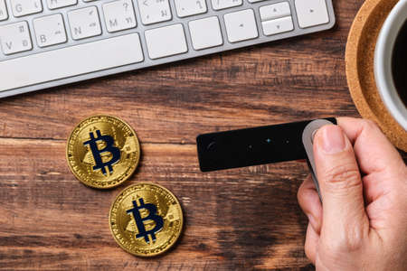 hand holding hardware wallet and transfer bitcoin and ethereum crypto currency to wallet for safetyの写真素材