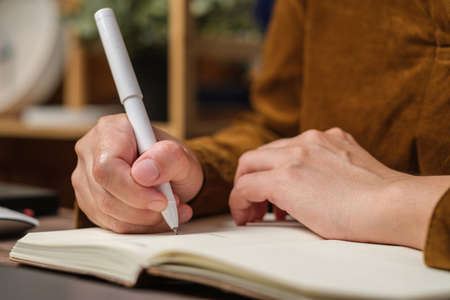 close uop woman hand writing on notebook at worknig desk at homeの写真素材