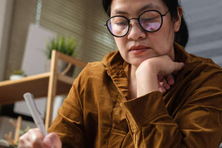 asian woman hand writing on notebook at worknig desk at homeの写真素材