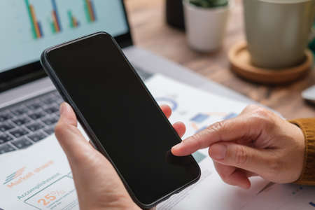 close up woman using mobile phone when working at desk at homeの写真素材