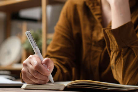 close uop woman hand writing on notebook at worknig desk at homeの写真素材