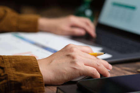 close up hand using mouse and typing on laptop keyboard when woking at homeの写真素材