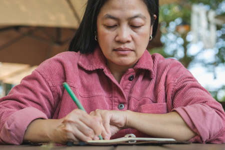 woman writing goal on notebook  at coffee shop outdoor spaceの写真素材