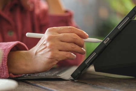 close up woman hand use pen working with tablet online at coffee shopの写真素材