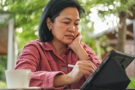asian woman working with tablet online at coffee shopの写真素材