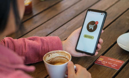 woman shopping online with credit card at coffee shop in outdoor.close up hand holding smartphoneの写真素材