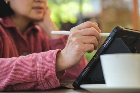 close up woman hand use pen working with tablet online at coffee shopの写真素材