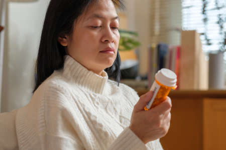 asian woman reading pill prescription when get flu on soaf at homeの写真素材