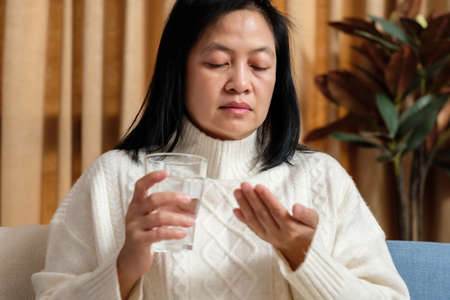 asian woman taking pill when get sick at homeの写真素材