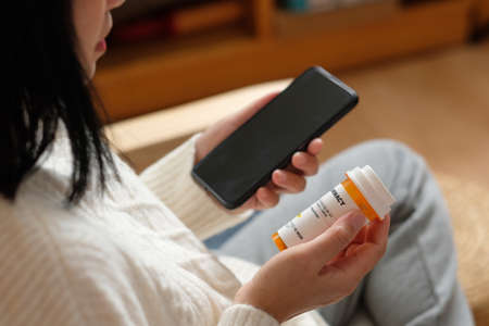 asian woman reading pill prescription when get flu on soaf at home