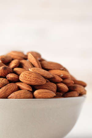 Almonds in ceramic bowl on white wood table.organic Diet raw material