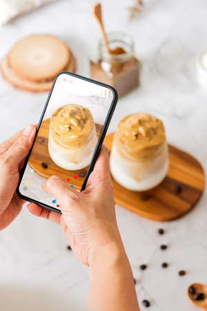 Dalgona coffee with fluffy cream served on wood tray.Homemade trendy beverage menu on social mediaの写真素材