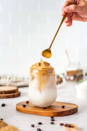 Dalgona coffee with fluffy cream served on wood tray.Homemade trendy beverage menu on social mediaの写真素材