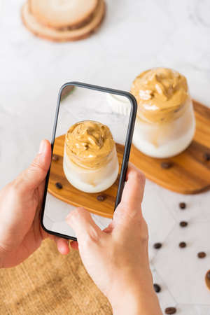 Dalgona coffee with fluffy cream served on wood tray.Homemade trendy beverage menu on social mediaの写真素材