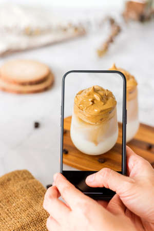 Dalgona coffee with fluffy cream served on wood tray.Homemade trendy beverage menu on social mediaの写真素材
