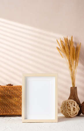 blank photo frame with wicker stuff on cement table and peach wallの写真素材