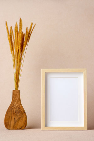 blank photo frame with pampas grass in wood vase at peach color backgroundの写真素材